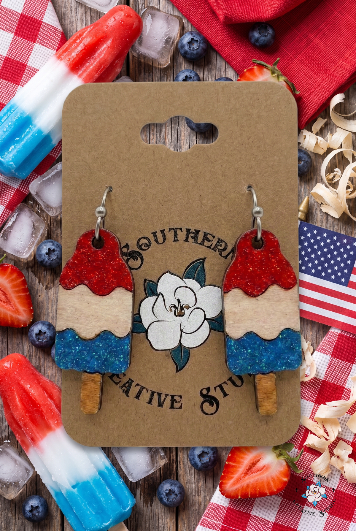 Bomb pop popsicle earrings flat lay with popsicles, berries and gingham on kraft card