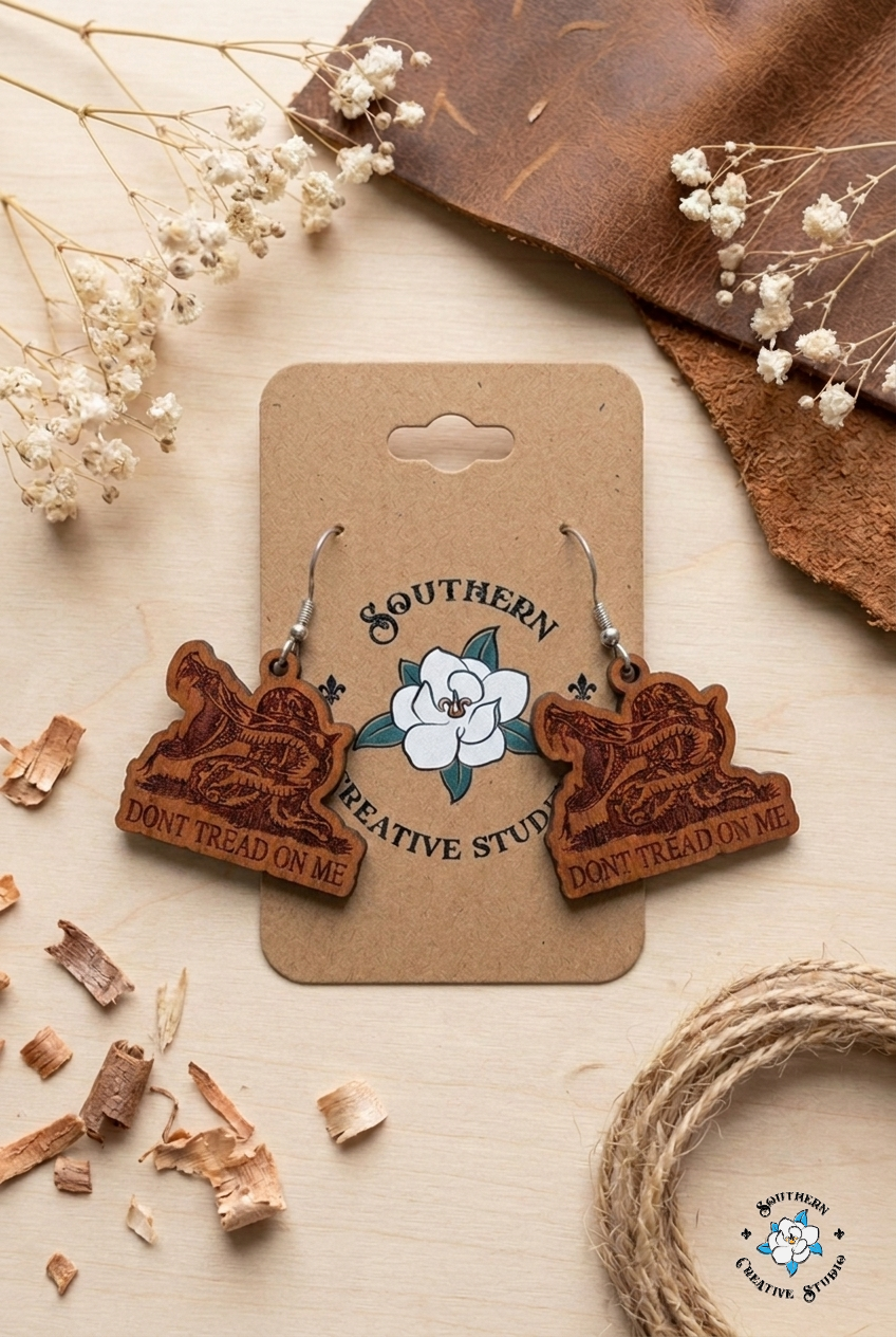 Flat lay moodboard of Don't Tread On Me snake hand-painted wood earrings on Southern Creative Studio card