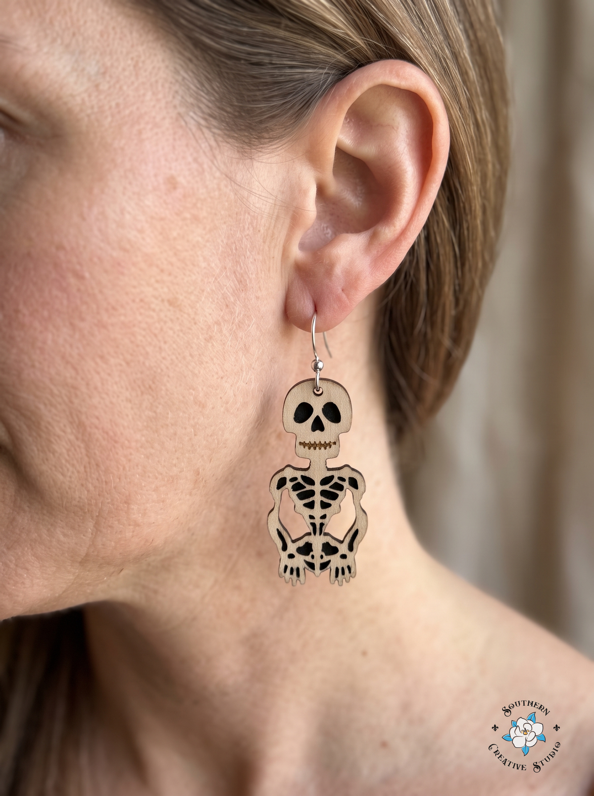 Close-up of wood skeleton dangle earring worn in ear