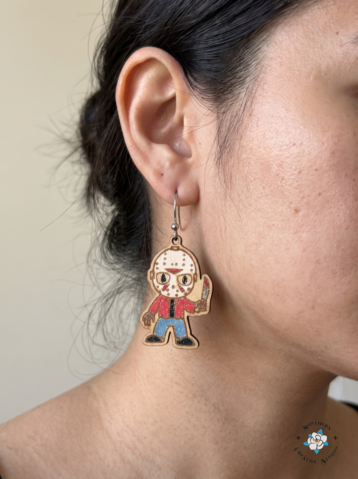 Close-up of woman wearing hand-painted wood hockey mask slasher earring