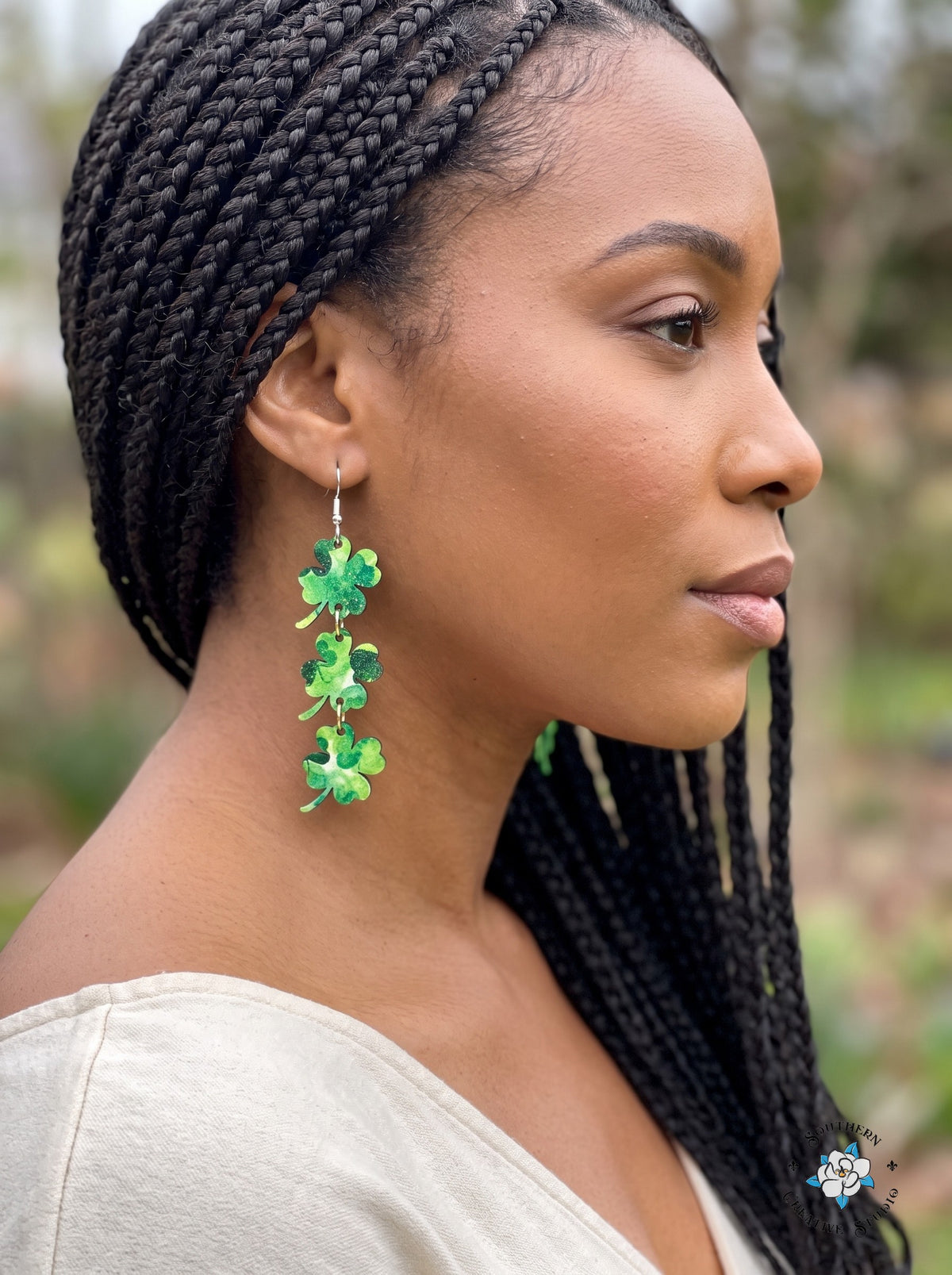 Woman wearing long marbled four leaf clover dangle earrings