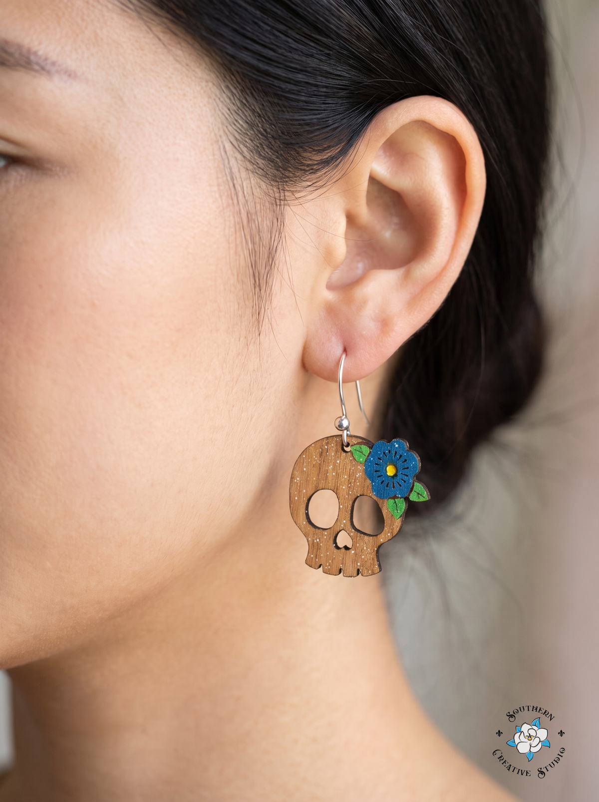 Woman wearing flower skull dangle earring with silver hook close-up