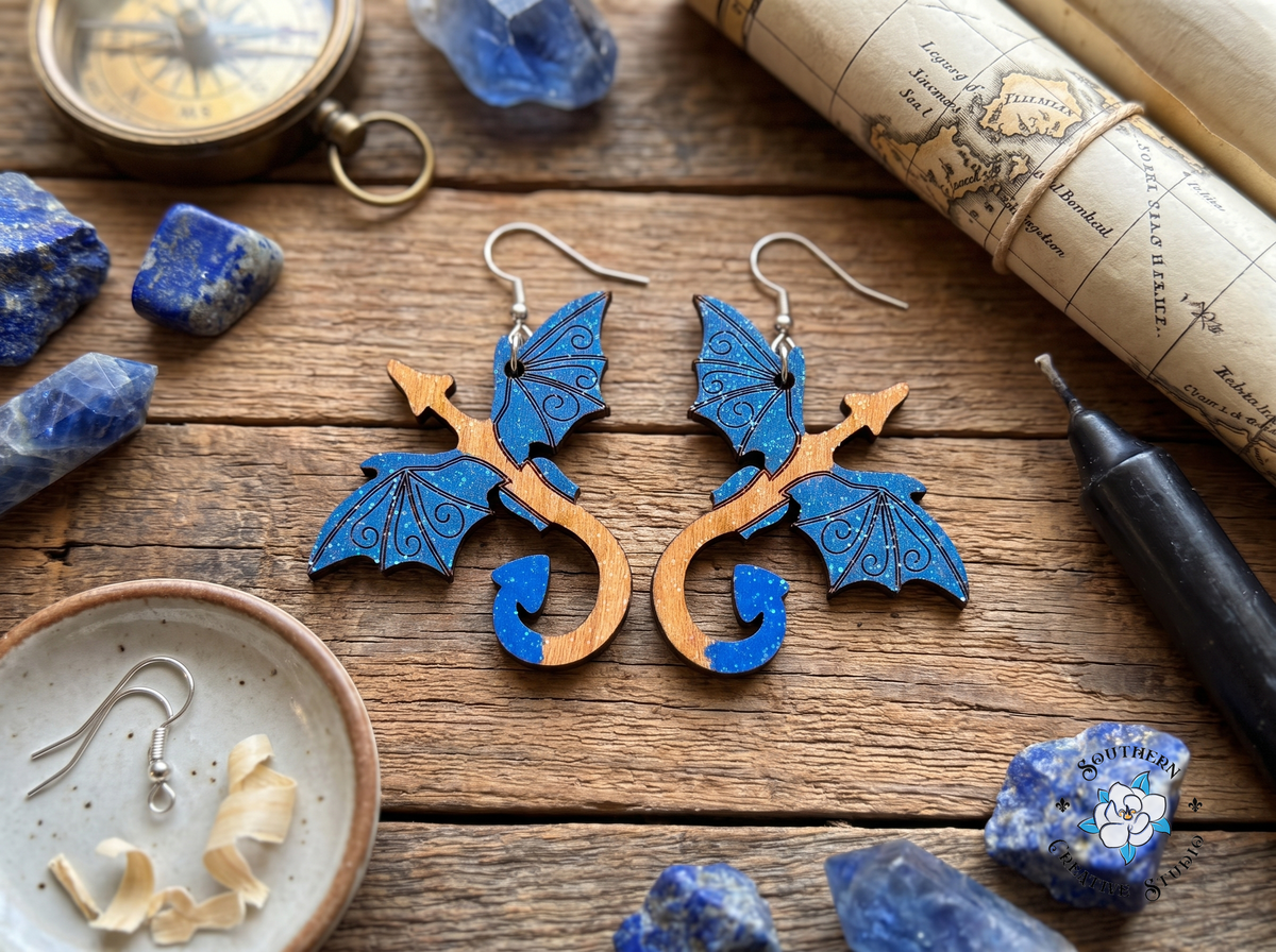 Blue dragon wood earrings on rustic table with lapis lazuli, brass compass and sea-chart map