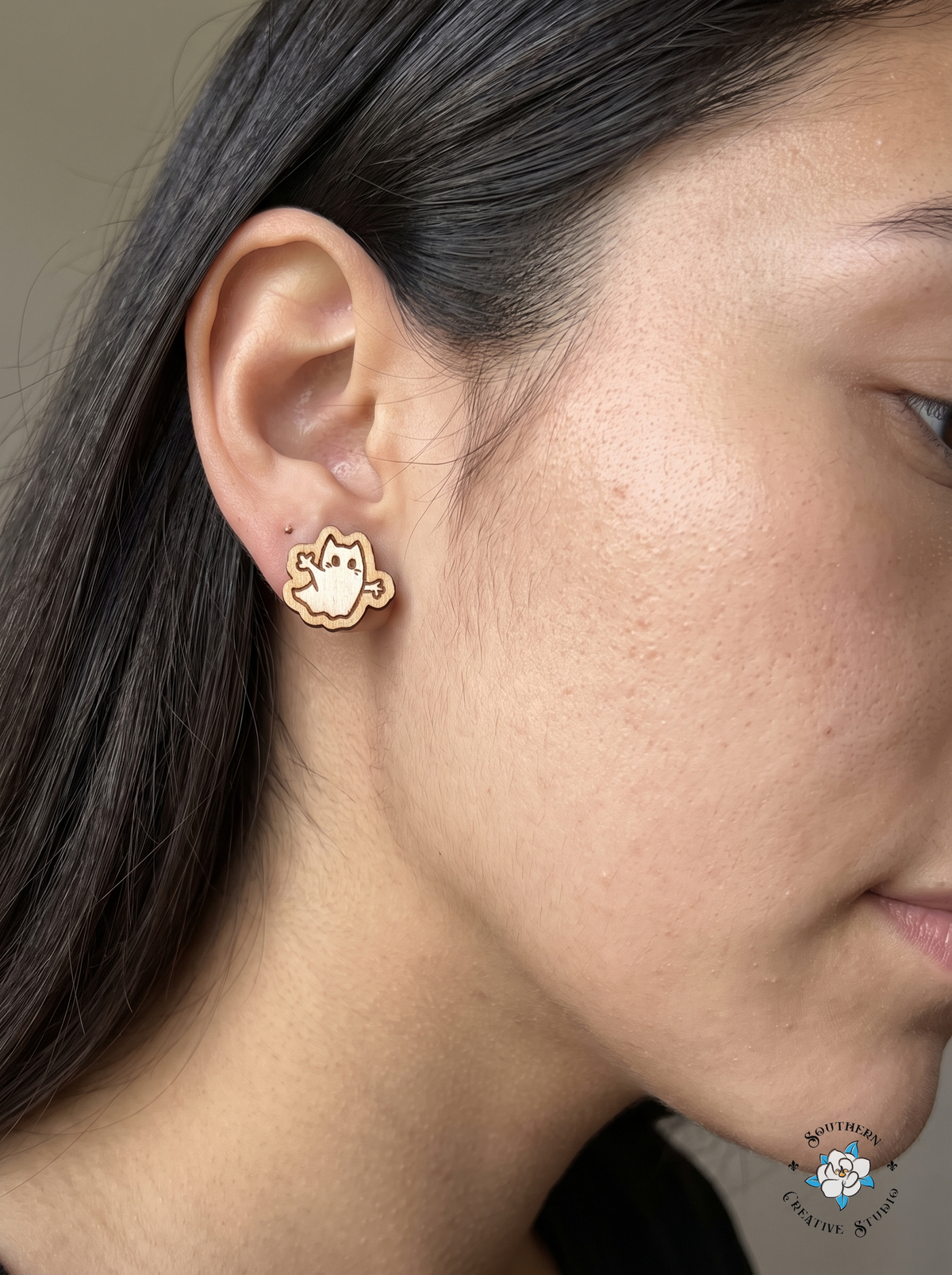 Close-up of wood ghost cat stud earring worn in ear