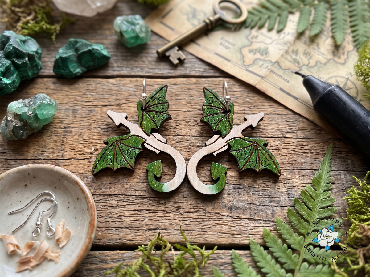 Forest green dragon wood earrings on rustic table with malachite crystals, antique key, forest map and ferns