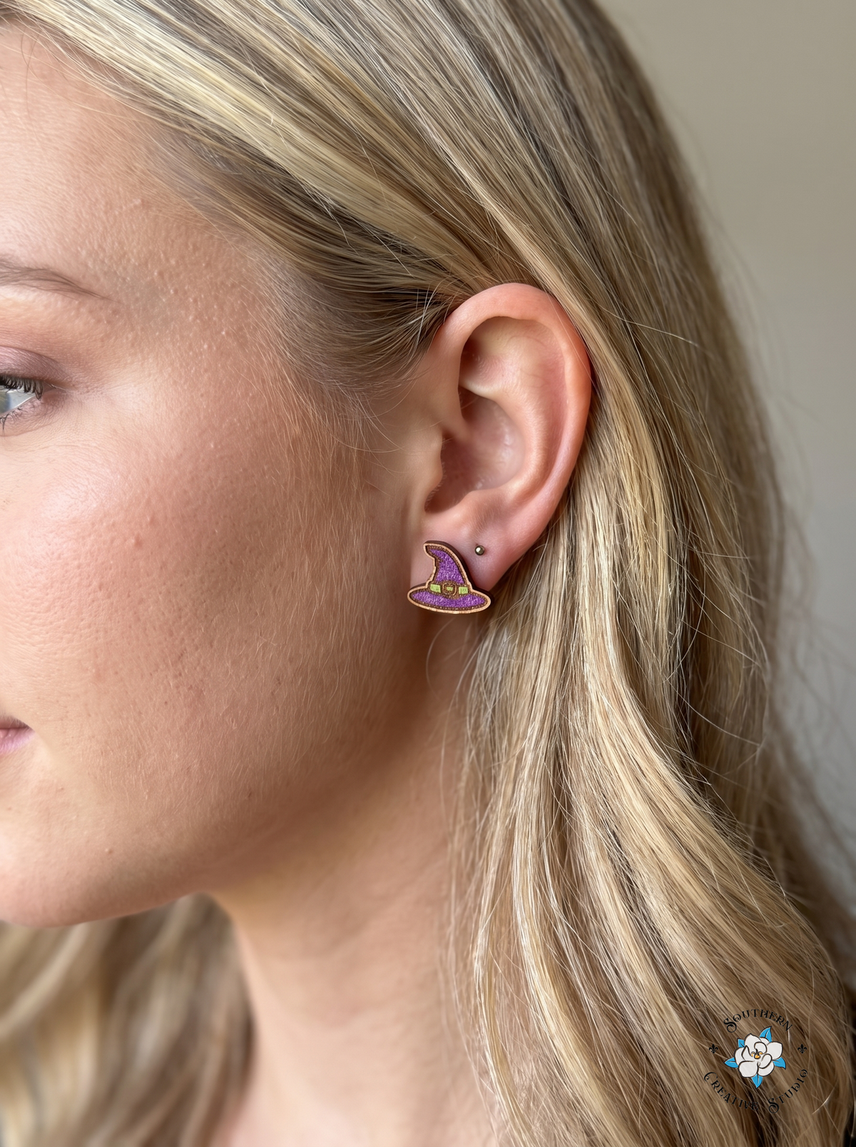 Close-up of purple witch hat wood stud earring worn in ear