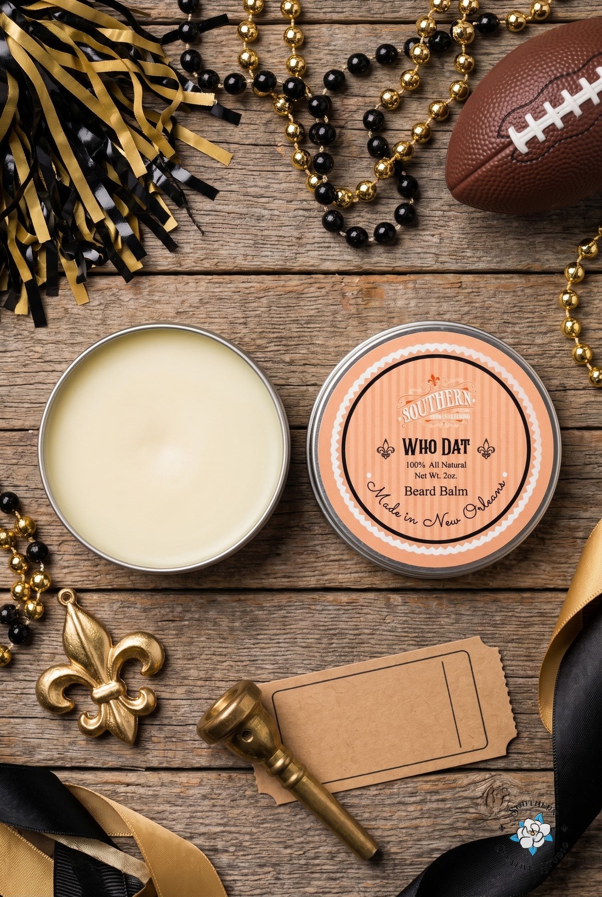 WhoDat beard balm flat lay, open tin and lid with black and gold Saints game-day with a fleur-de-lis and beads