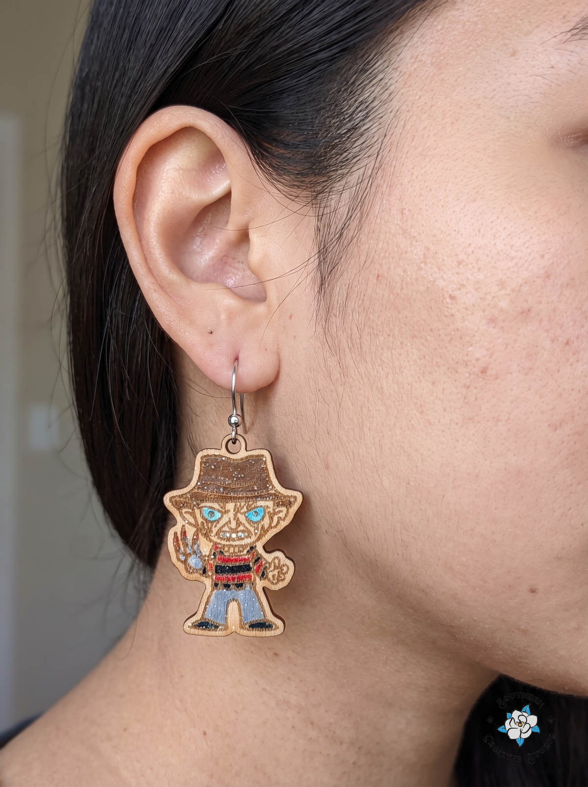 Woman wearing hand-painted wood slasher horror movie dangle earring