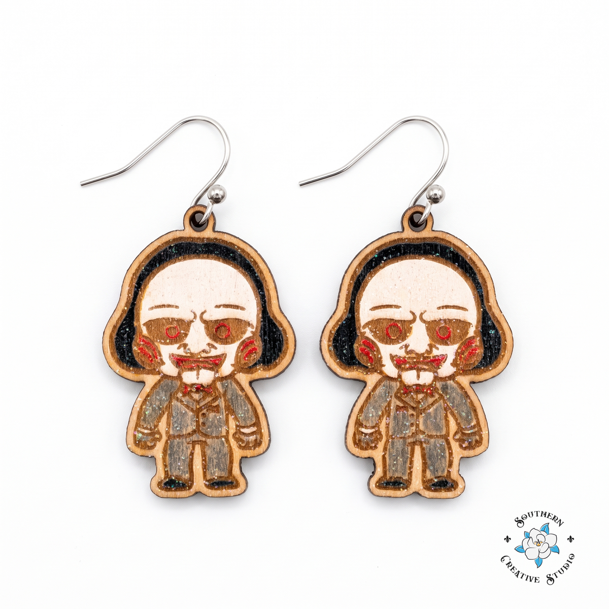 Creepy puppet hand-painted wood dangle earrings with red spiral cheeks and red bow tie on white background