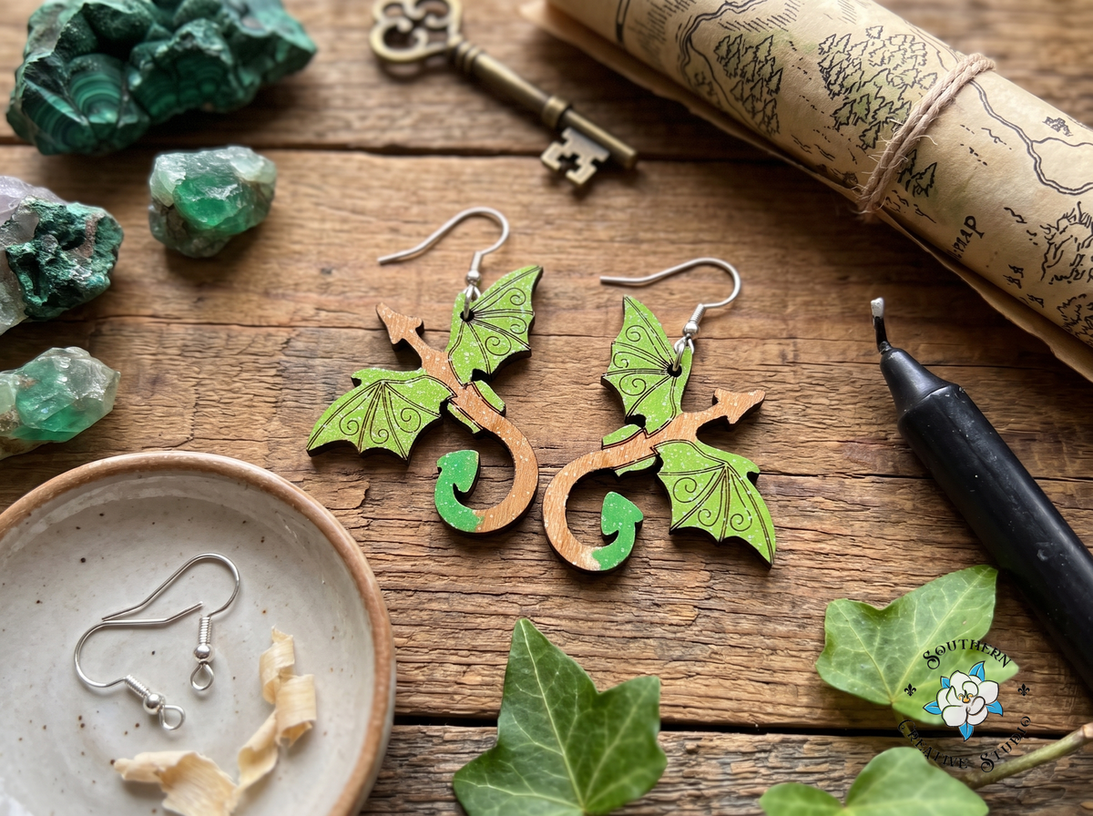Green dragon wood earrings on rustic table with malachite crystals, antique key, forest map and ivy