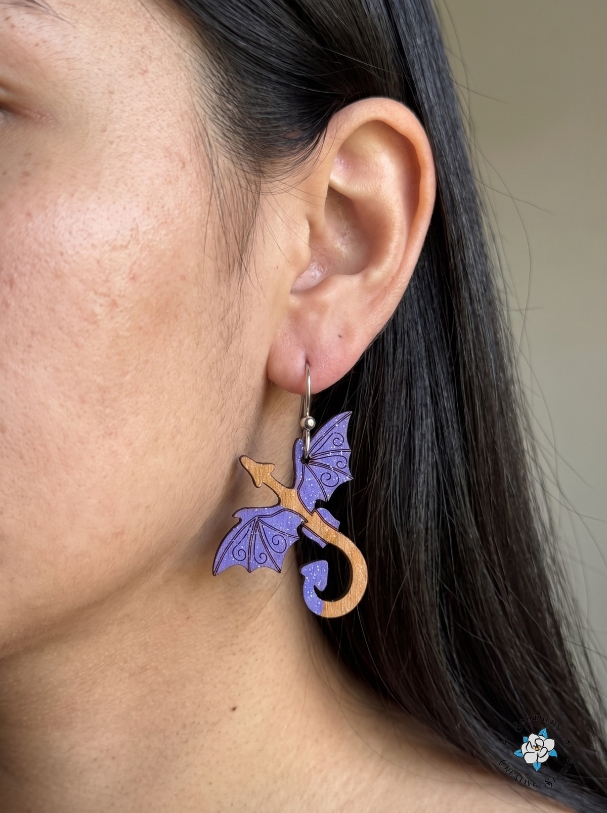 Woman wearing hand-painted wood purple dragon fantasy dangle earring