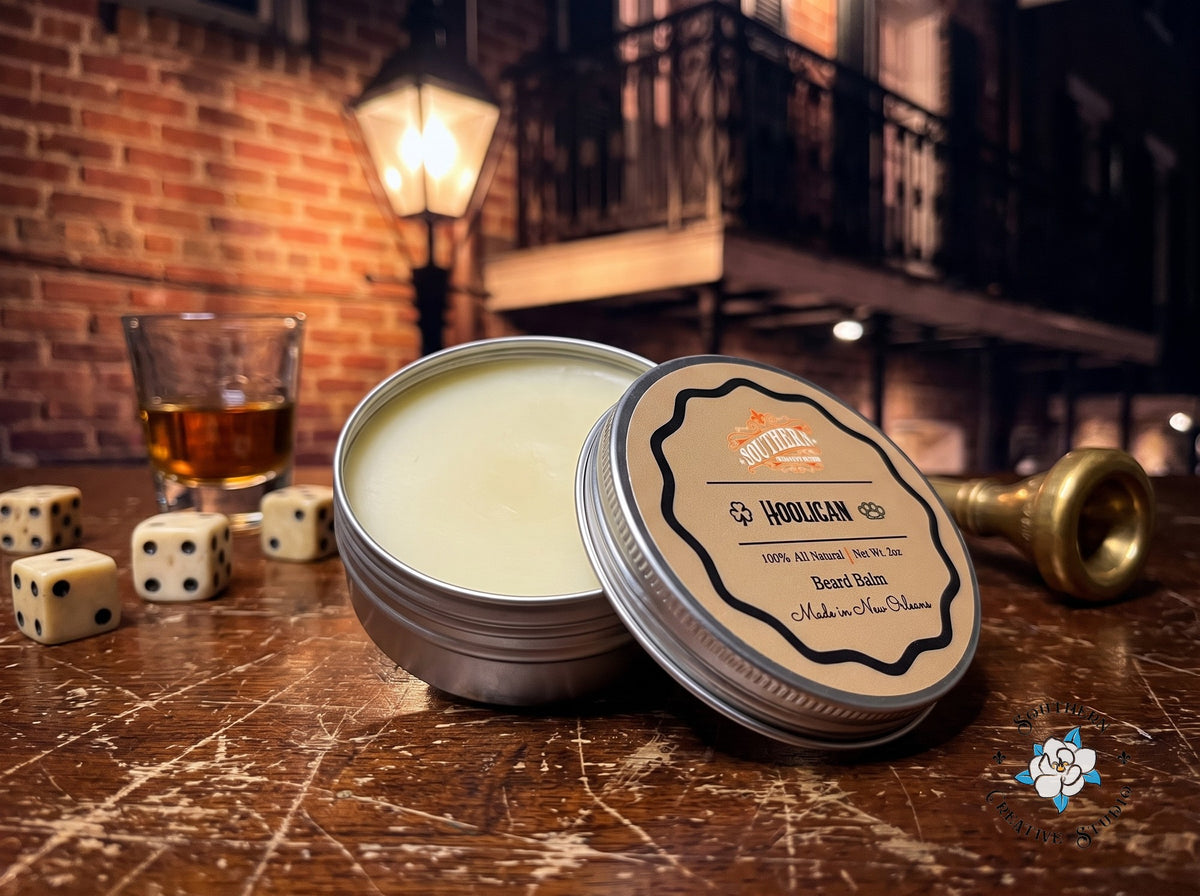 Hooligan beard balm close-up, open tin with leaning lid and a night-time French Quarter table with dice, whiskey and a brass trumpet mouthpiece