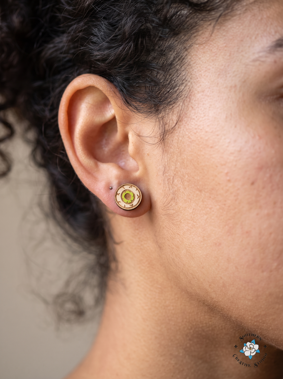 Close-up of green eyeball wood stud earring worn in ear
