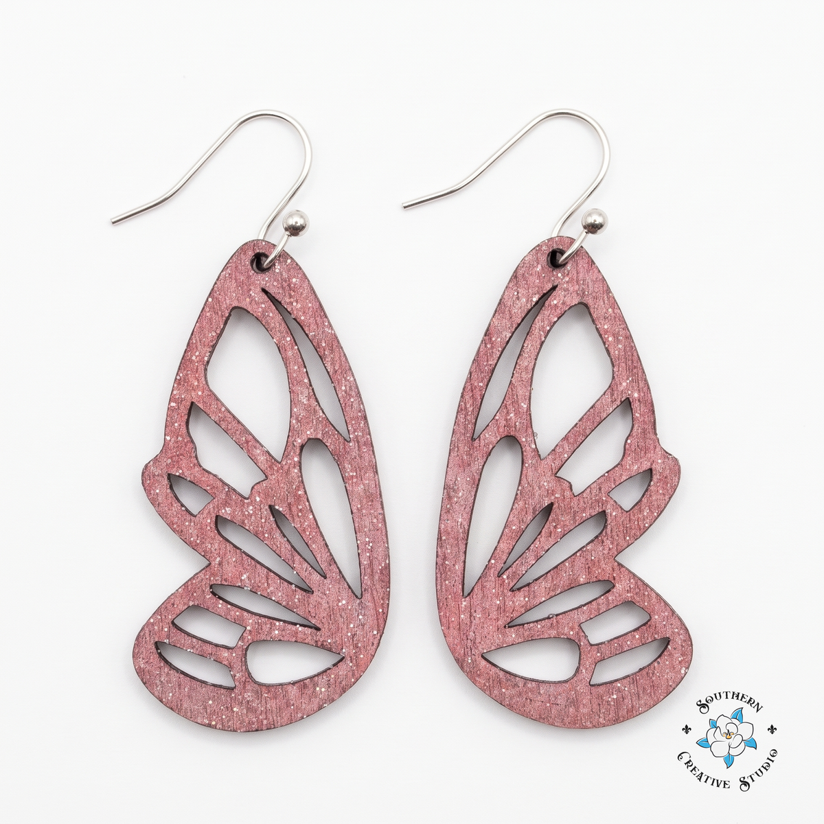 Pink butterfly wing earrings, hand-painted wood cutout dangles on white background
