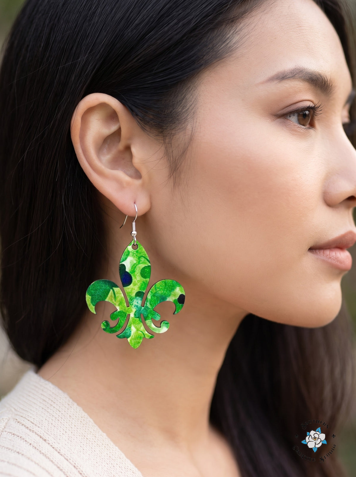 Woman wearing marbled green fleur-de-lis clover dangle earrings