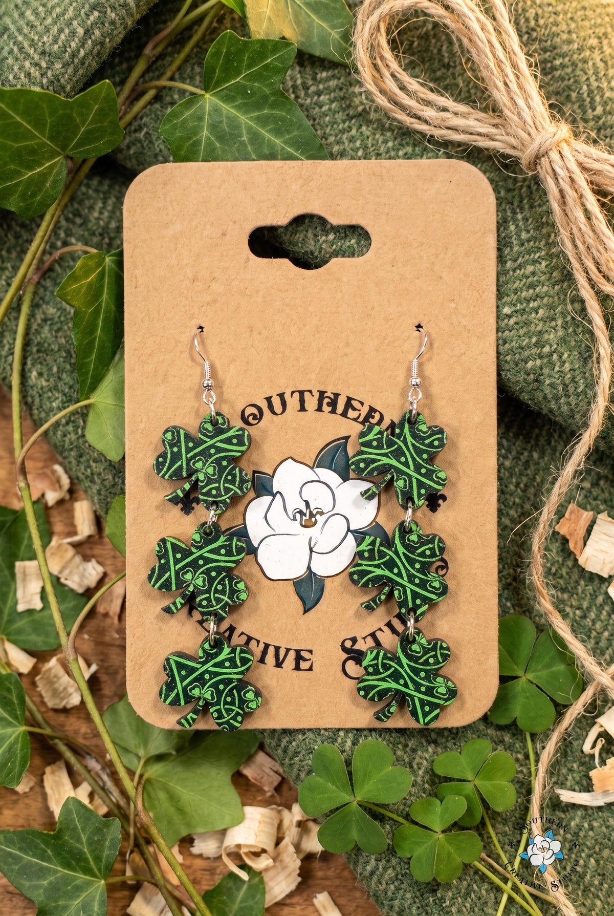 Celtic knot shamrock dangle earrings on card in a tweed and ivy flat lay