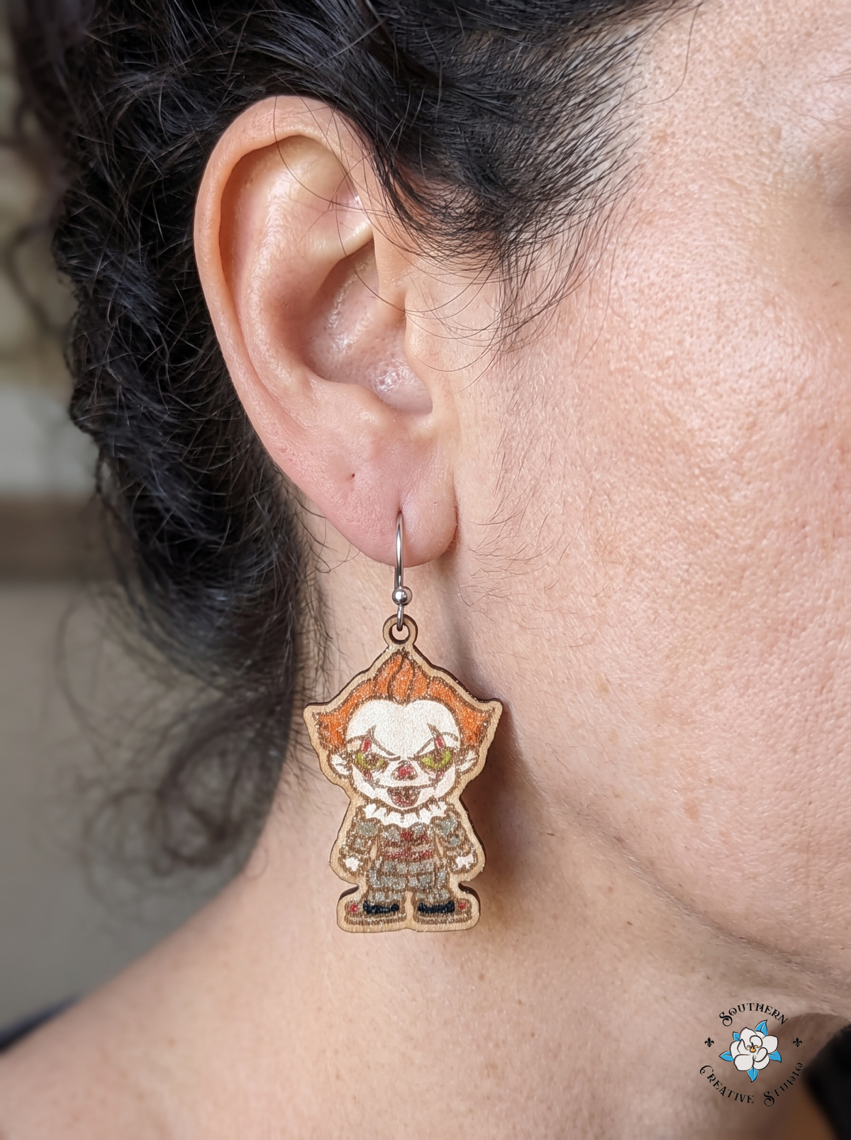 Close-up of woman wearing hand-painted wood creepy clown earring