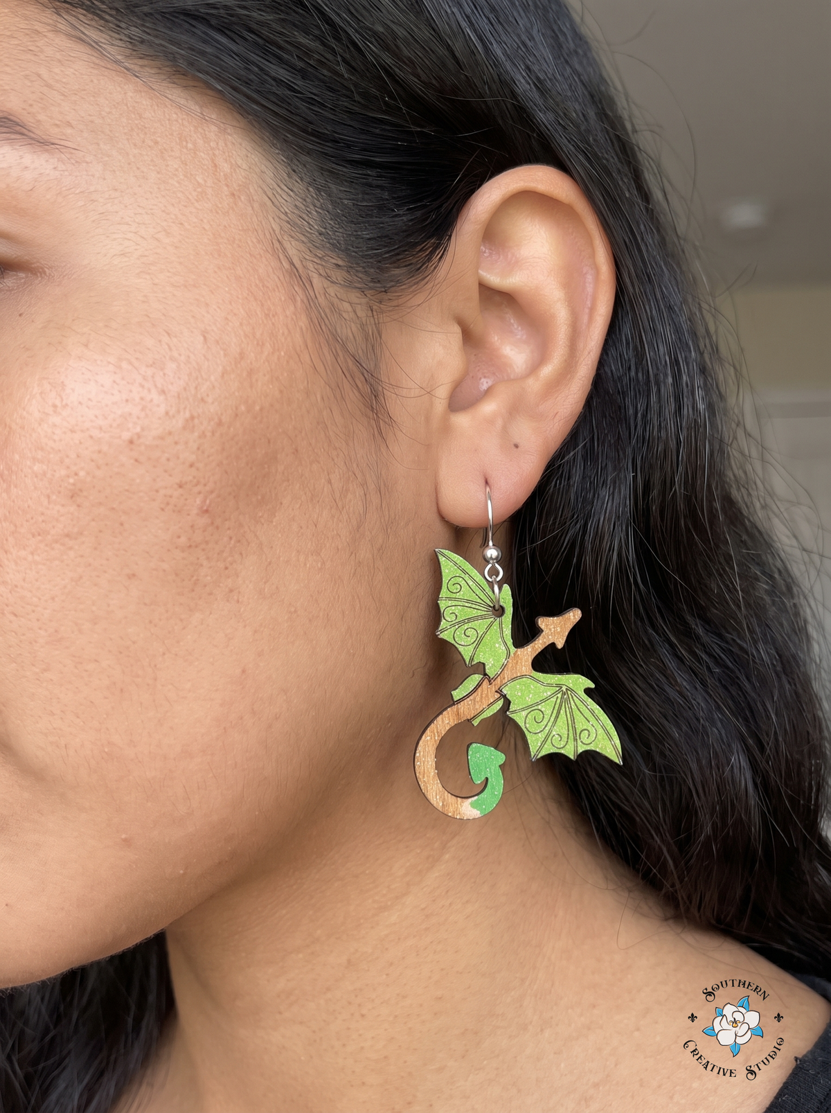 Woman wearing hand-painted wood green dragon fantasy dangle earring