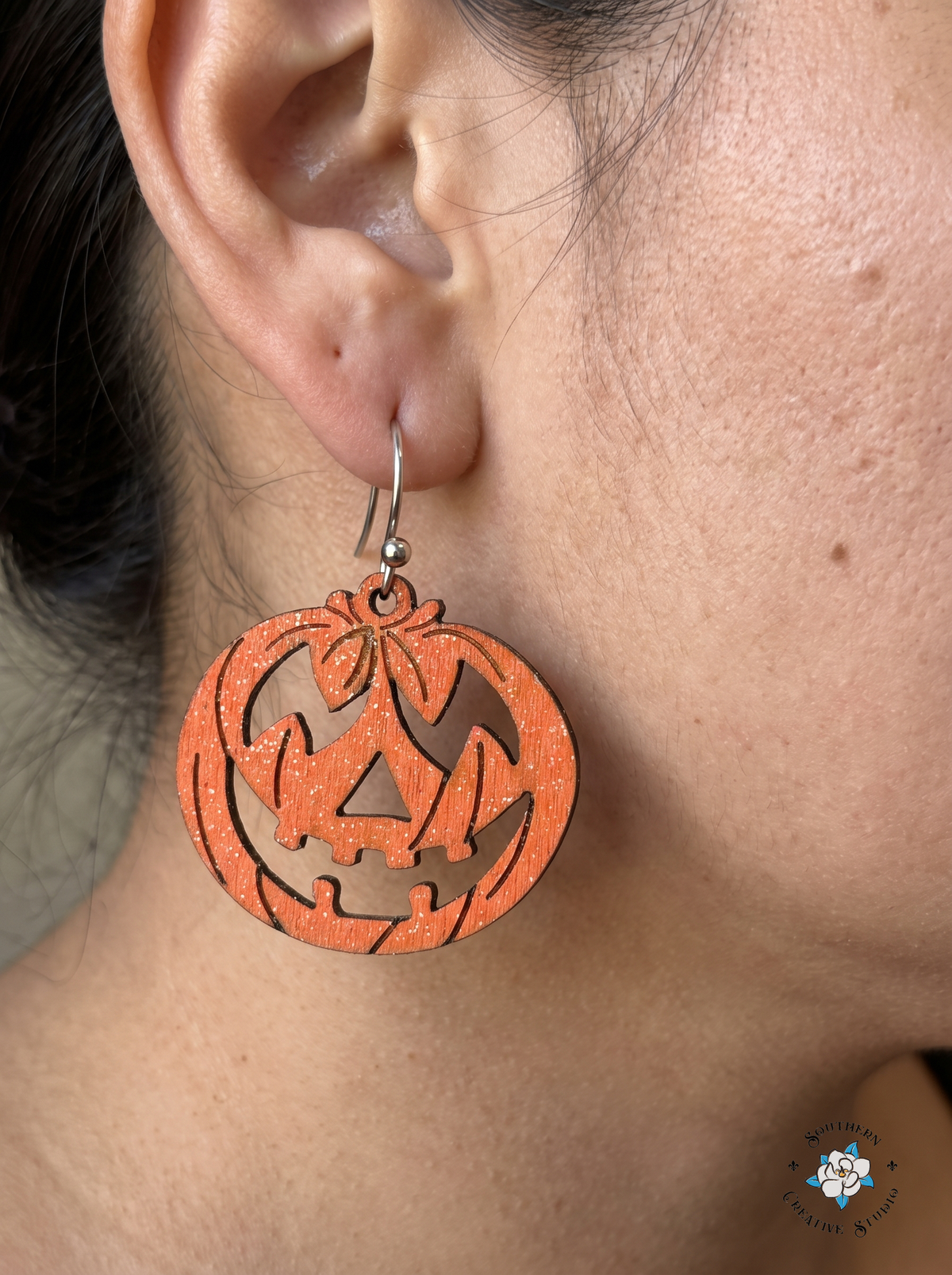 Close-up of woman wearing orange wood jack-o'-lantern earring