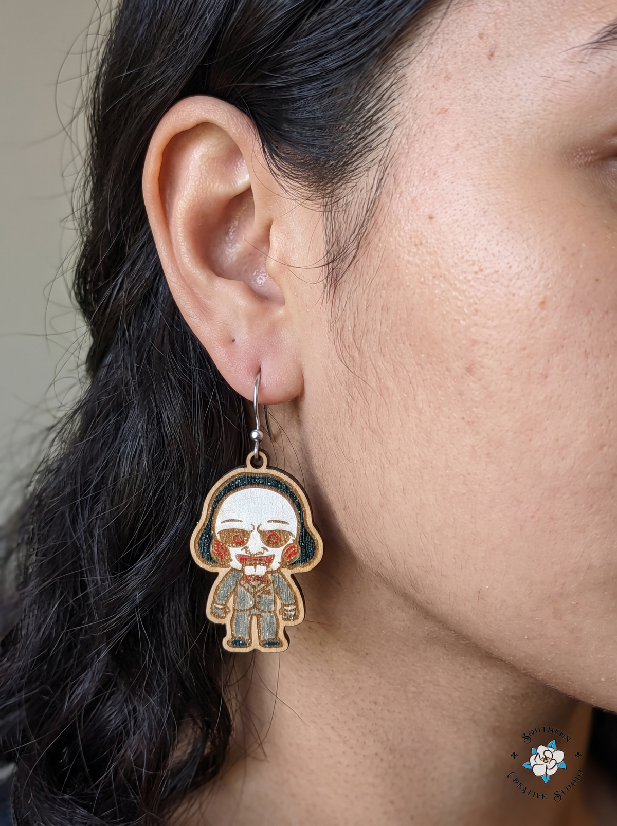 Woman wearing hand-painted wood creepy puppet horror movie dangle earring