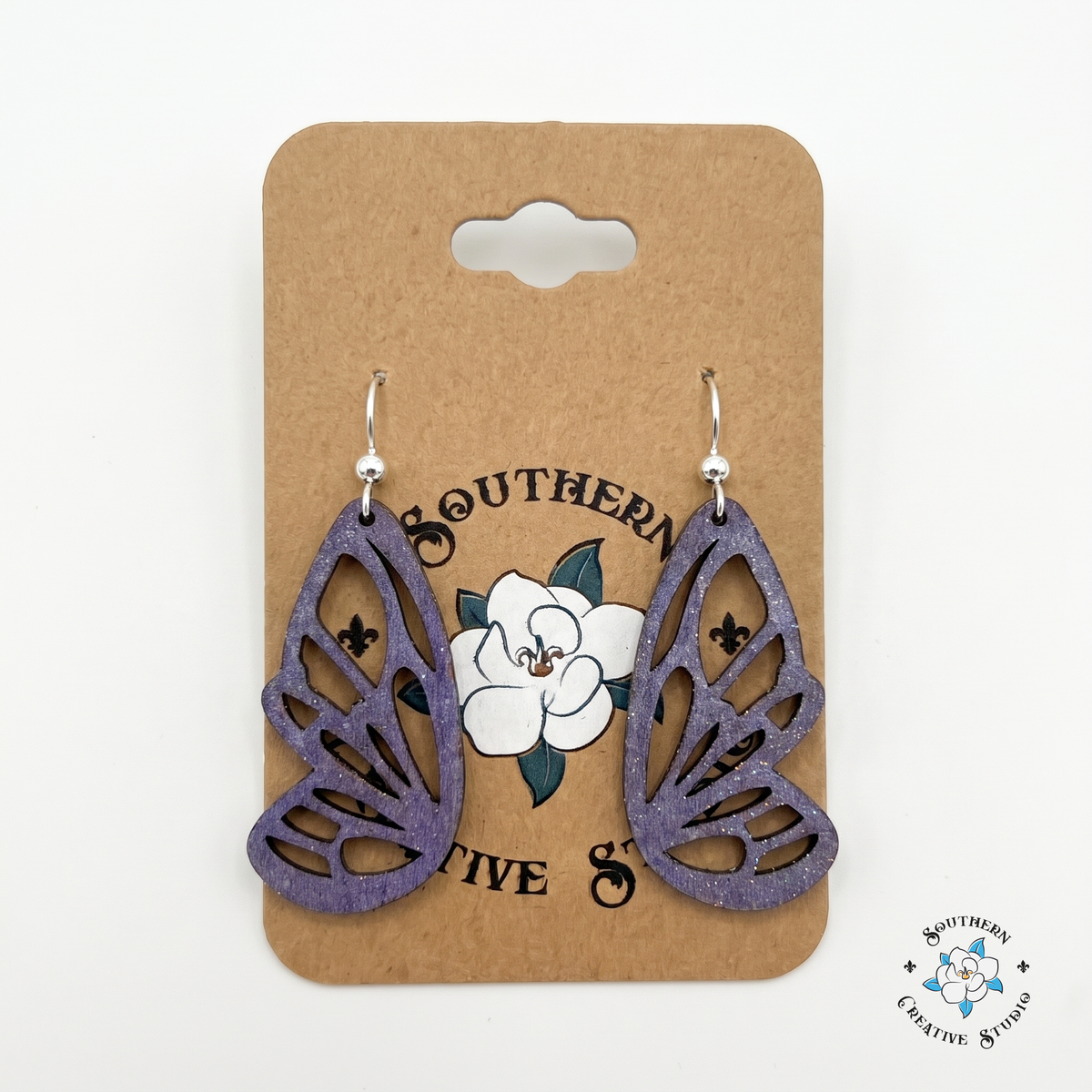 Hand-painted purple butterfly wing wood earrings on Southern Creative Studio kraft hang card