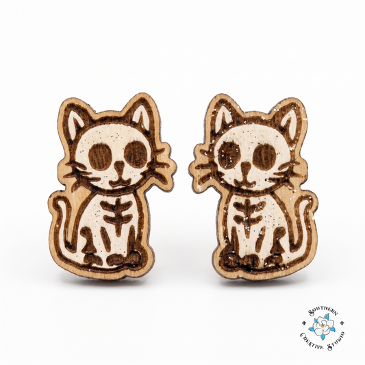 White-painted skeleton cat wood stud earrings on white background