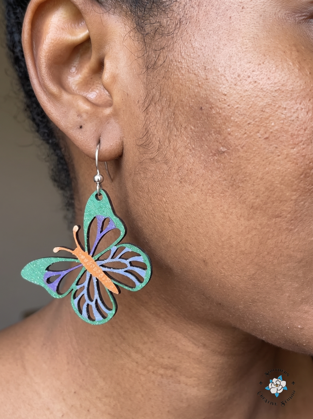 Close-up of woman wearing emerald butterfly wood dangle earring
