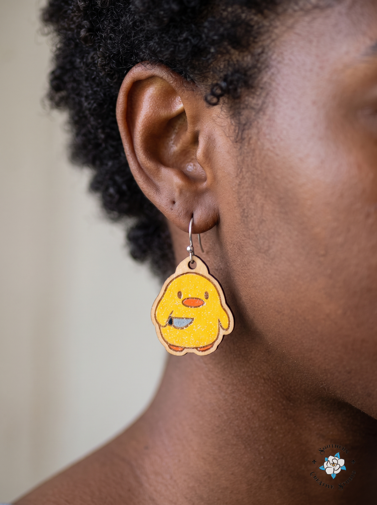 Woman wearing duck with knife dangle earring with silver hook close-up