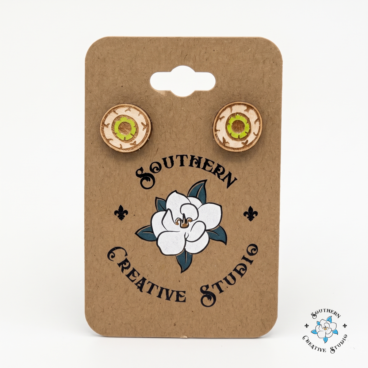 Green eyeball wood stud earrings on Southern Creative Studio hang card