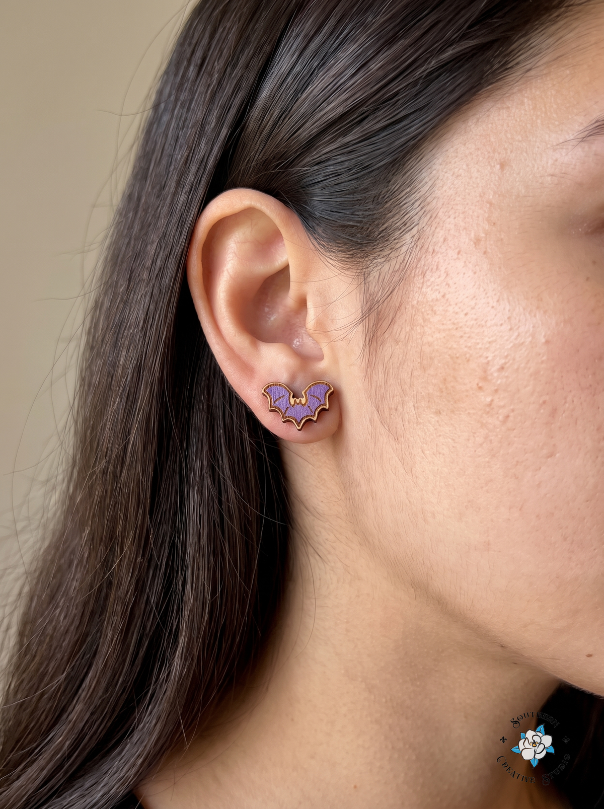 Close-up of purple bat wood stud earring worn in ear