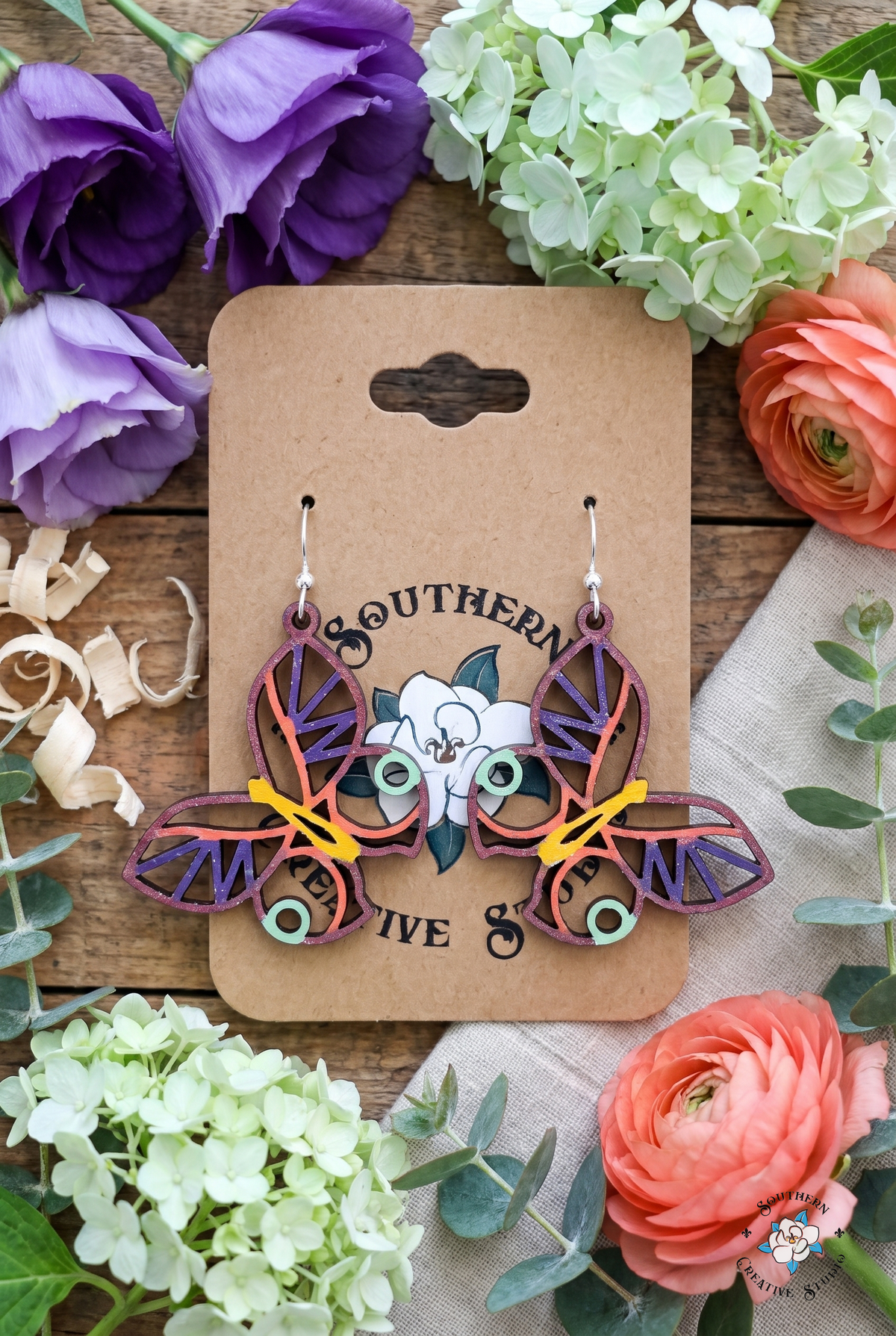 Mint circle butterfly earrings flat lay with purple lisianthus and coral ranunculus on kraft card