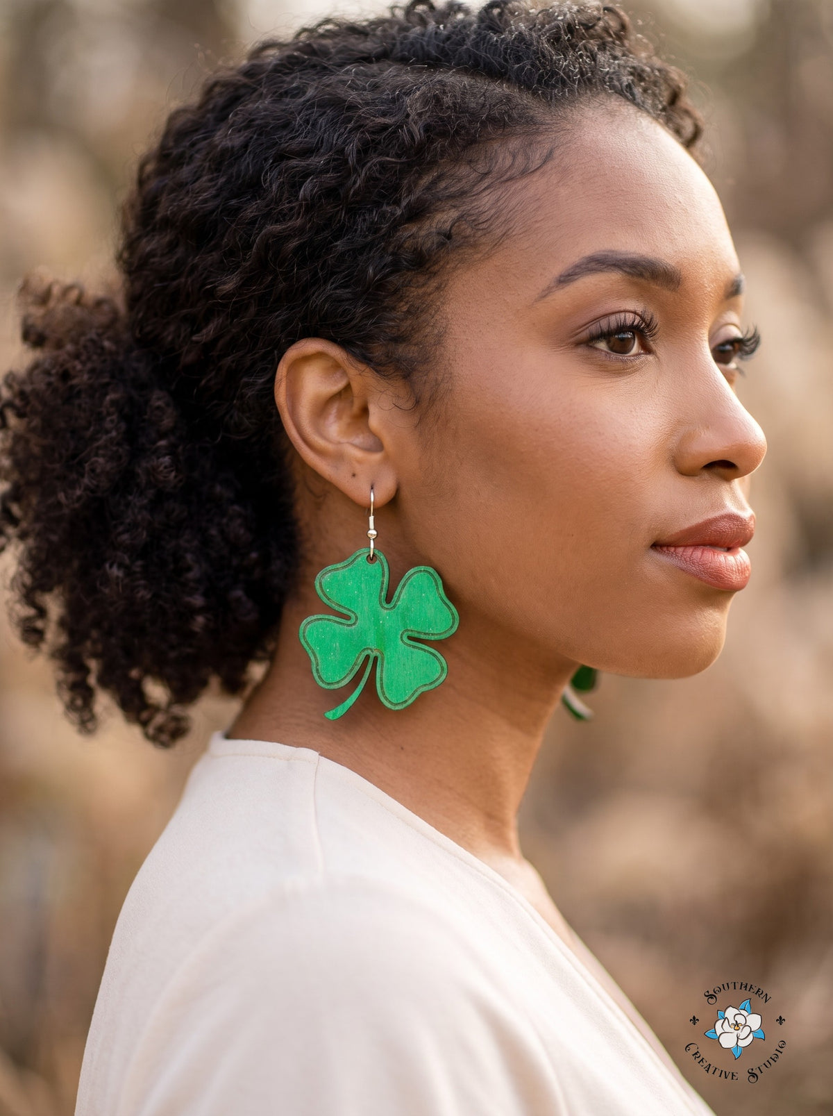 Woman wearing emerald green four leaf clover earrings