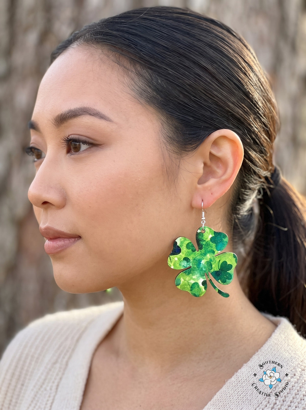 Woman wearing large marbled green four leaf clover earrings