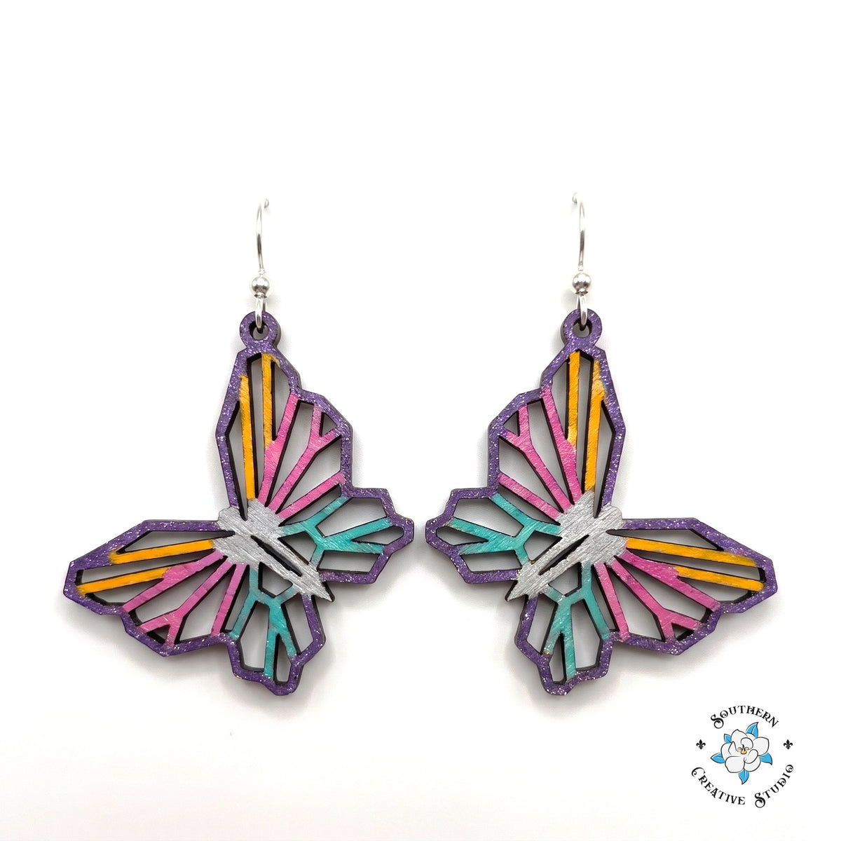Geometric butterfly earrings, open see-through layered hand-painted wood with purple edge and pink, yellow, teal stripes on white background