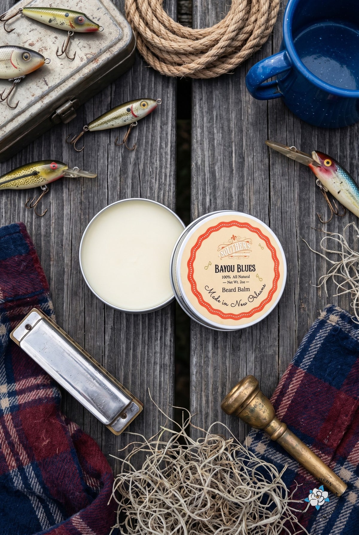 Bayou Blues beard balm flat lay, open tin and lid with a Louisiana bayou dock with fishing tackle, rope, harmonica and a trumpet mouthpiece