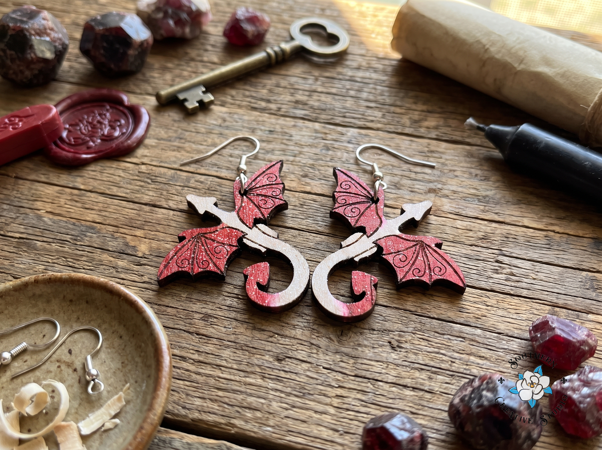 Red dragon wood earrings on rustic table with garnet crystals, antique key and wax seal
