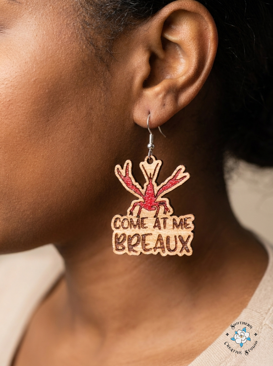 Close up of Come At Me Breaux crawfish hand-painted wood earring on ear