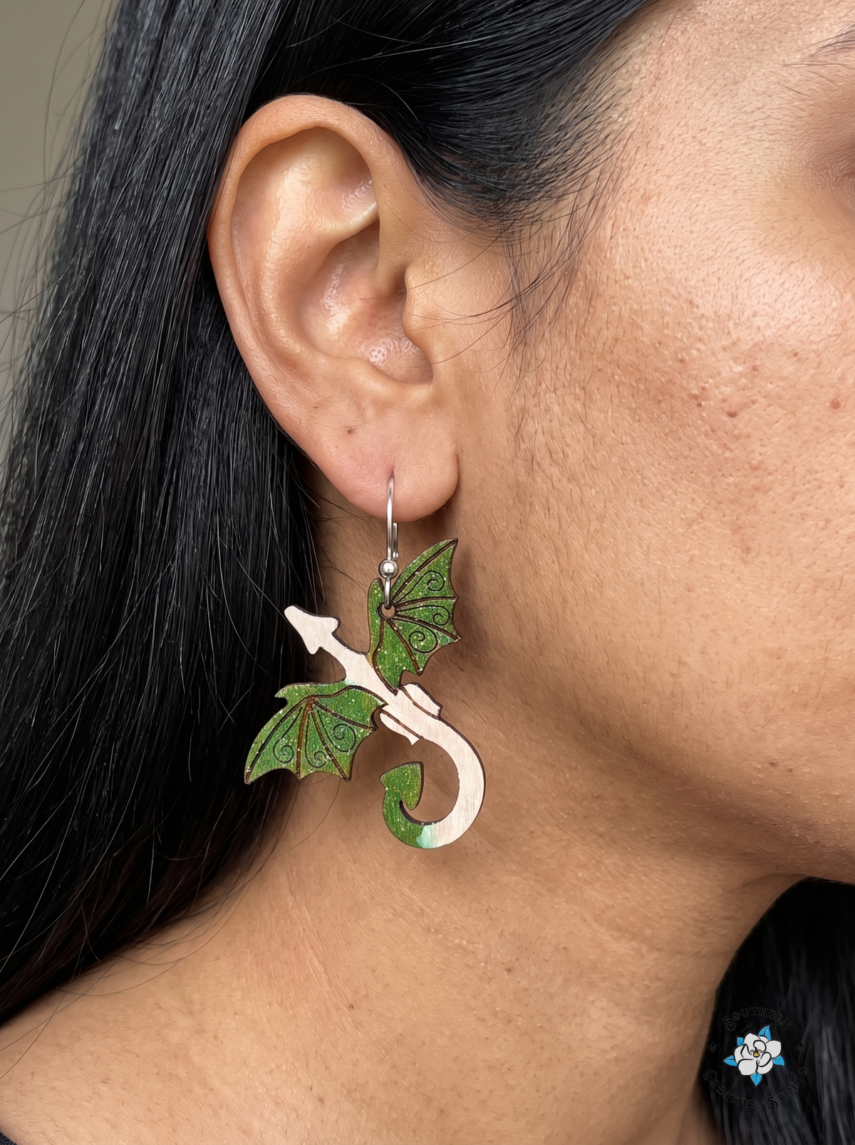Woman wearing hand-painted wood forest green dragon fantasy dangle earring