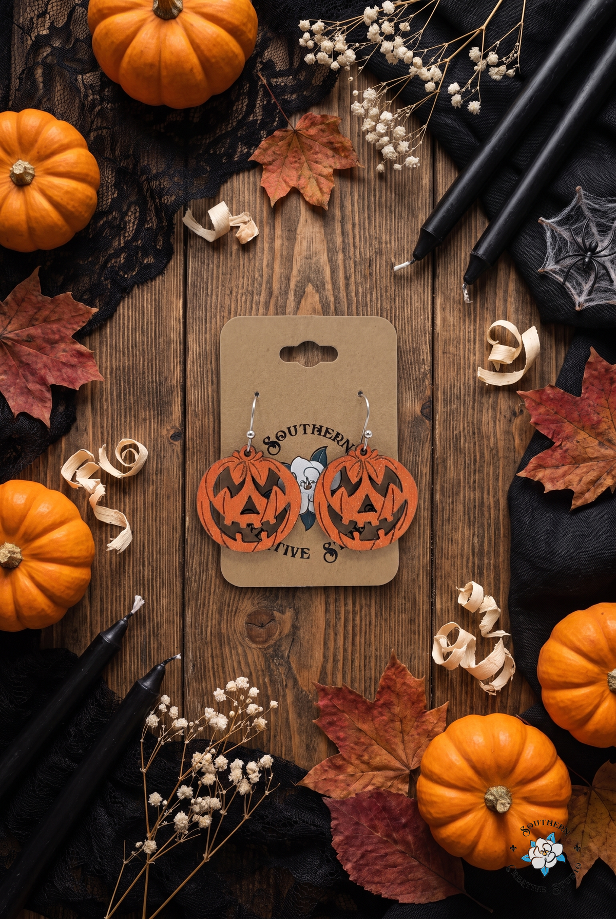 Halloween flat lay with jack-o'-lantern earrings, pumpkins and black candles