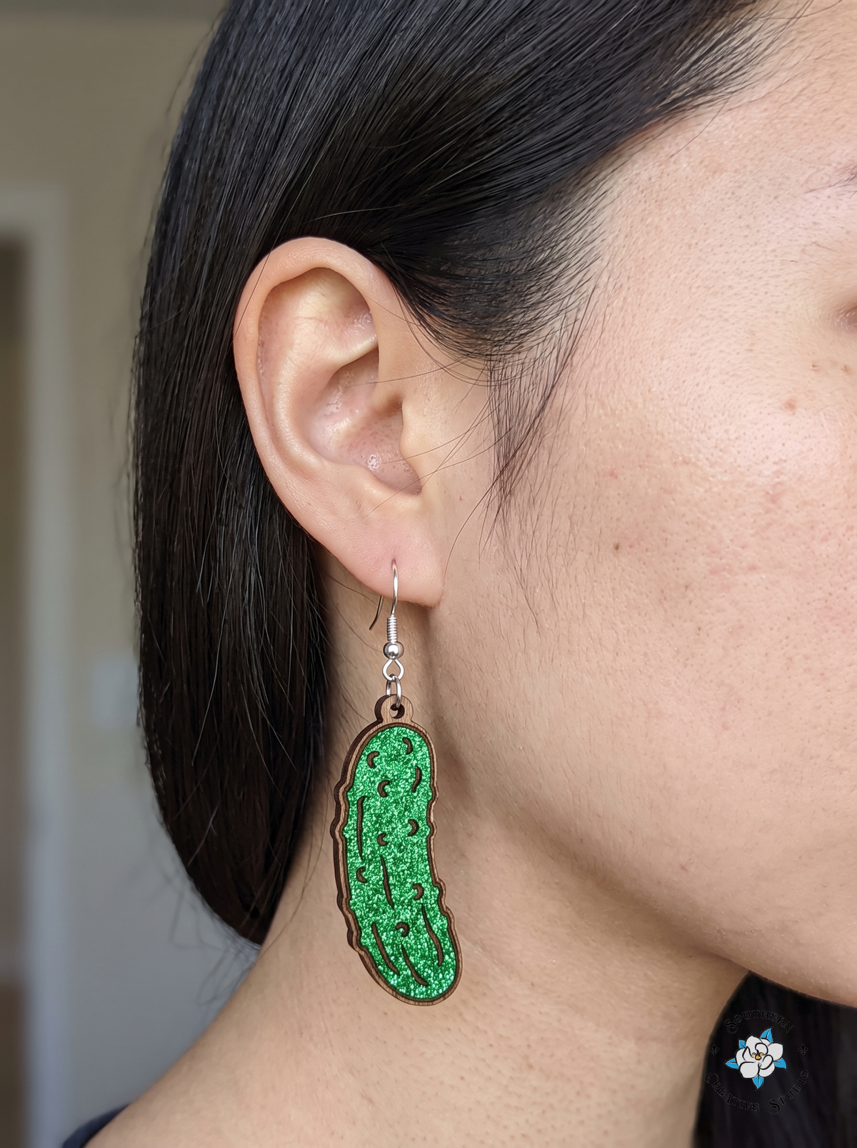 Woman wearing hand-painted green wood pickle dangle earring
