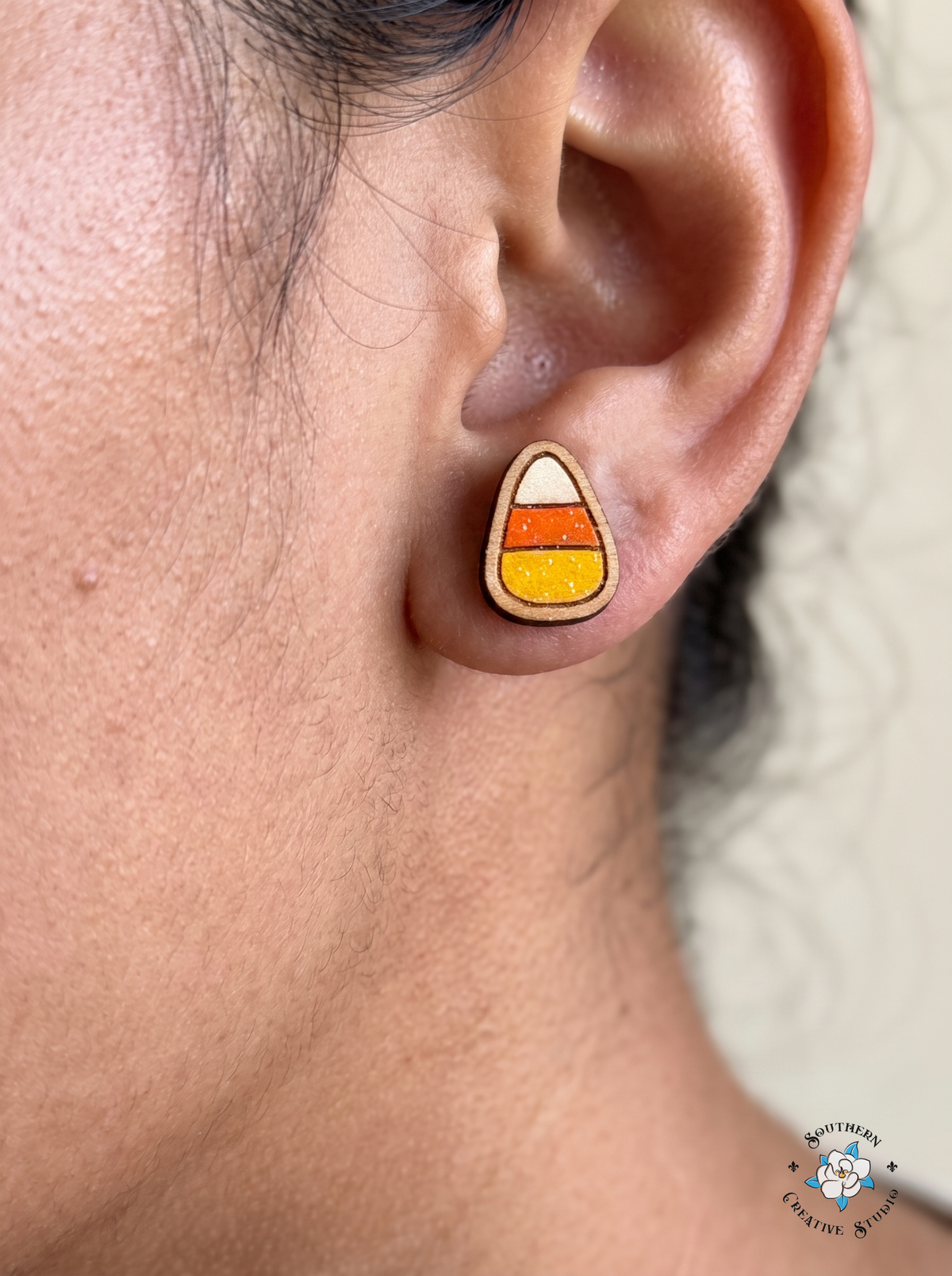 Close-up of woman wearing candy corn wood stud earring
