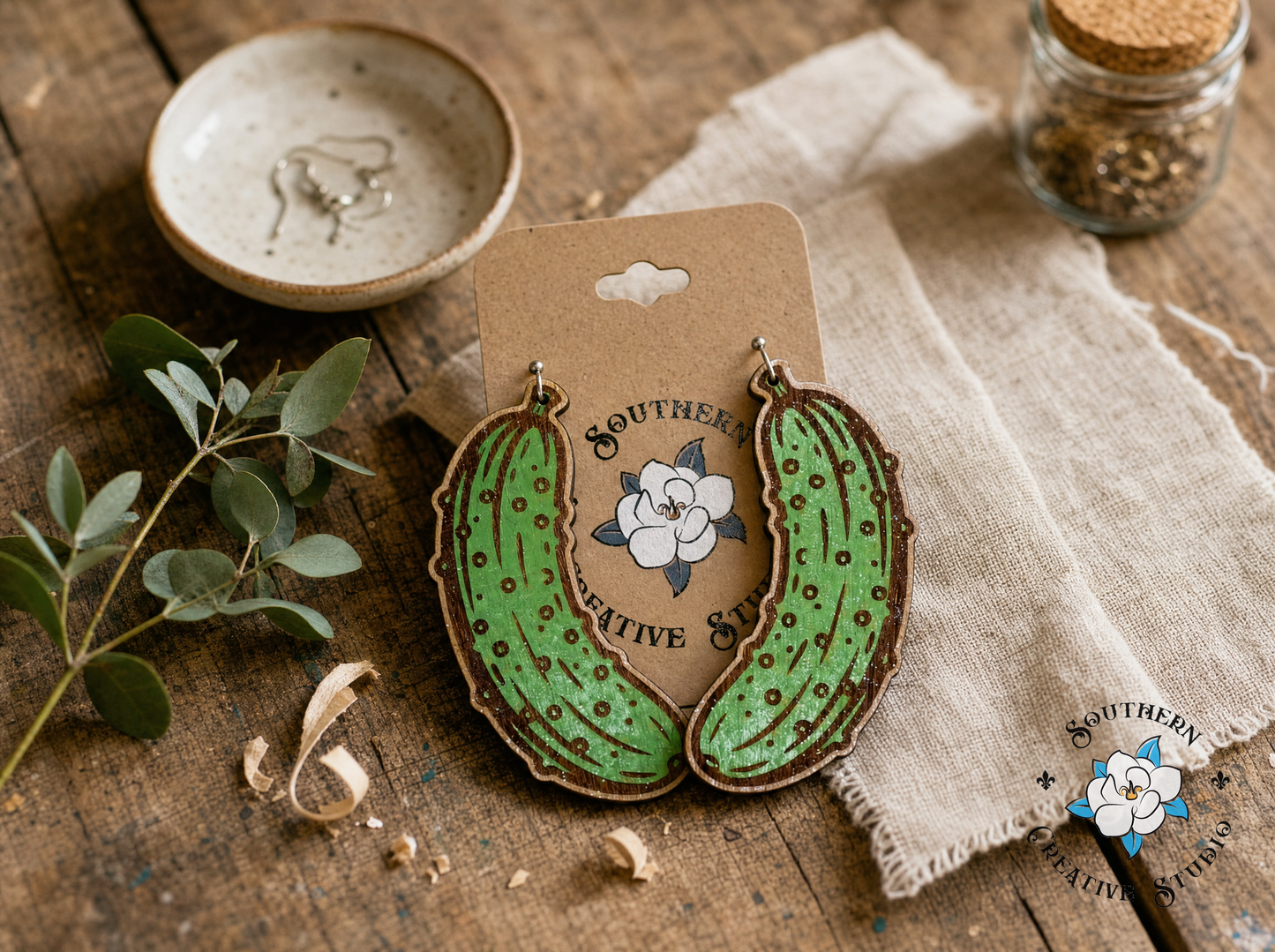 Handmade wood pickle earrings styled on rustic wood with greenery