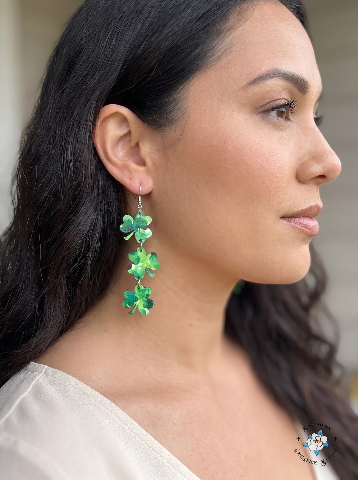 Woman wearing long marbled three leaf clover dangle earrings