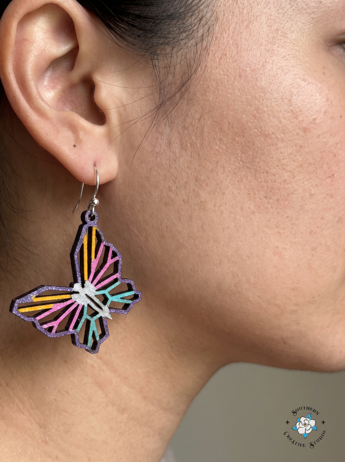 Close-up of woman wearing geometric butterfly wood dangle earring