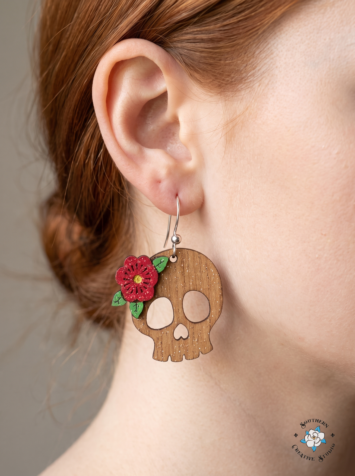 Woman wearing red flower skull dangle earring with silver hook close-up
