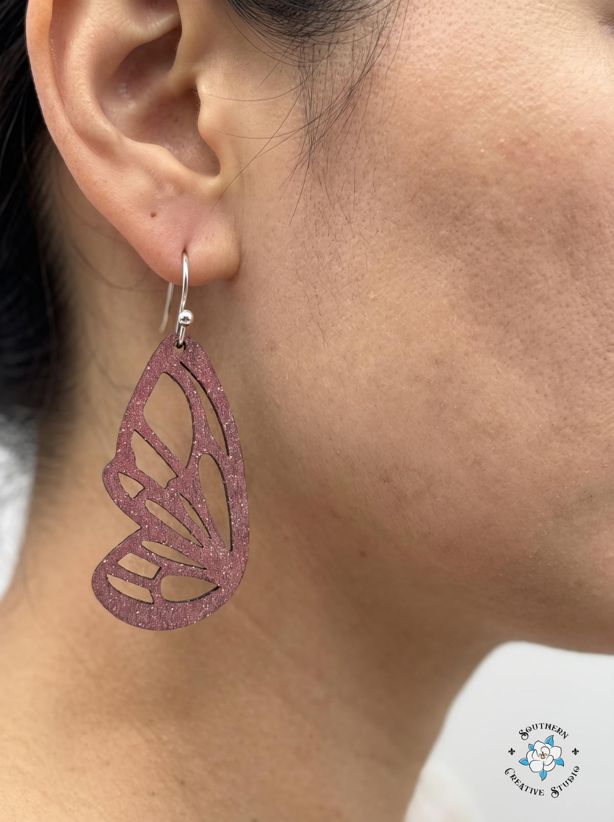 Close-up of woman wearing pink butterfly wing wood dangle earring