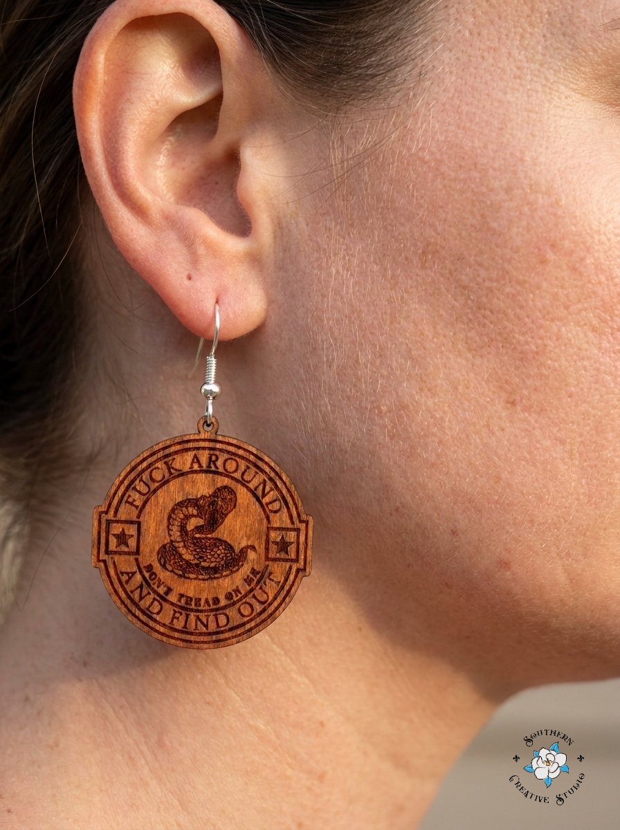 Close up of FAAFO snake medallion hand-painted wood earring on ear