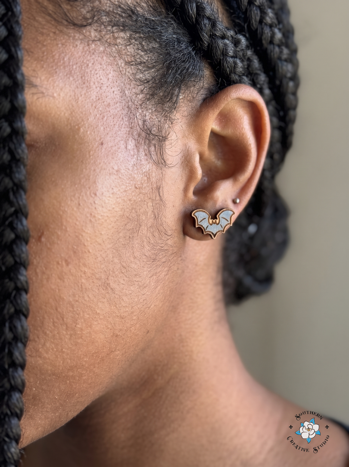 Close-up of gray bat wood stud earring worn in ear