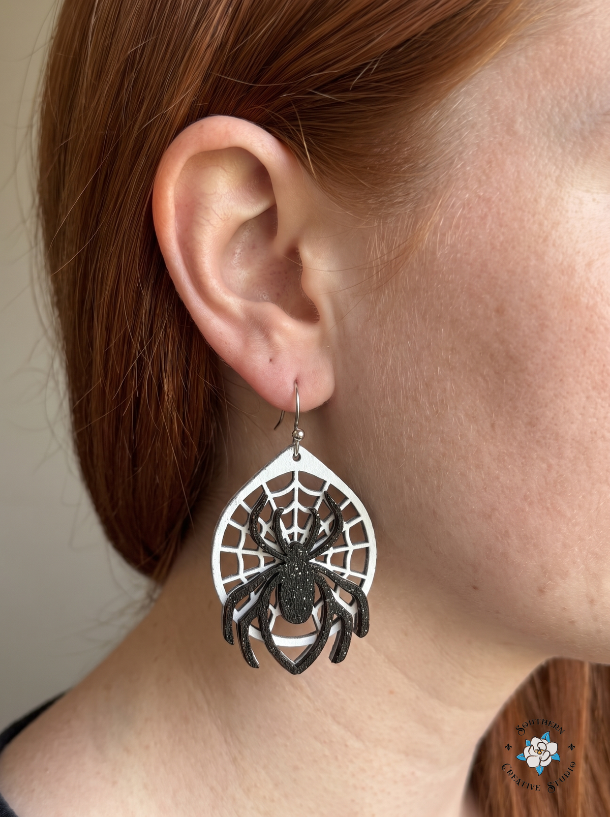 Close-up of spider web wood dangle earring worn in ear